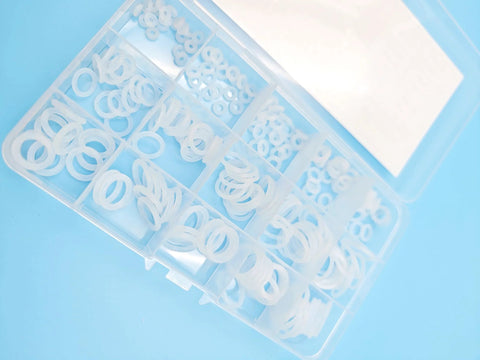 Overhead view of a clear plastic O-ring kit box with white silicone VMQ rings in 15 metric sizes (225 pieces).