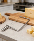 Rock Solid Stainless Steel Cheese Slicer Accessories For Hard Cheddar And Butter No Sweat Wire Cutter on countertop with cheeses.