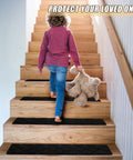 Child walking on wooden stairs with black 8 By 30 Inch Stair Treads 15 Piece Non Slip Peel and Stick Indoor Rug Runner for Wooden Steps.