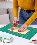 Person using a cutting wheel on a Cutting Mat 12 By 18 Inch Self Healing Double Sided For Sewing And Quilting Fabric Cutting Mat
