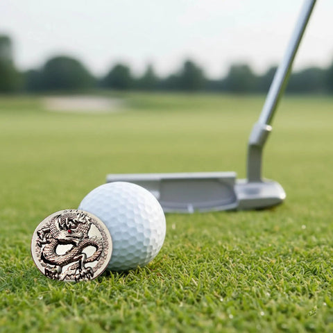 Dragon Golf Ball Marker With Hat Clip, Crystal Red Eye Design, shown on grass beside golf club and ball during on course play.