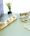 Clear Acrylic 3 Hole Punch For 10 Sheets With Four And A Quarter Inch Hole Spacing Gold Accents on a desk with office supplies