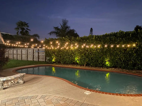 Solar Powered Outdoor String Lights 48 Ft Commercial Grade Waterproof Patio Lights illuminating a backyard pool area