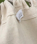 Close-up of cotton fabric and tag of Handmade Cotton Woven Hammock Chair With Rope Swing And Crochet Fringe For Indoor Outdoor Patio Backyard Garden Boho Vibes Natural White Built For Cozy Relaxation And Easy Indoor Or Outdoor Living
