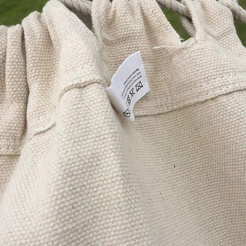Close-up of cotton fabric and tag of Handmade Cotton Woven Hammock Chair With Rope Swing And Crochet Fringe For Indoor Outdoor Patio Backyard Garden Boho Vibes Natural White Built For Cozy Relaxation And Easy Indoor Or Outdoor Living
