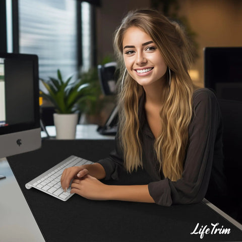 Woman working at desk with Huge 46 By 17 Inch XXL Thick Gaming Mouse Pad For Gamers, black color, under white keyboard.
