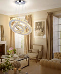 Lit Three Ring LED Chandelier With Changeable Color Temperature in a living room with beige decor and large windows.