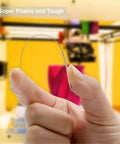 Close-up of a hand holding a flexible 0.4mm stainless steel cleaning needle from the 3D Printer Nozzle Cleaning Kit 13 Piece Set