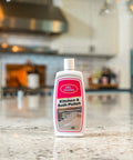 Real Deal Carnauba Wax Kitchen And Bath Polish Removes Scratches Stains Water Spots Protects Fiberglass Marble Acrylic Ceramic Chrome Stainless Steel 16 Oz Jar displayed on a clean kitchen countertop.