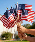 Hands holding 12 Pack Small American Flags 4x6 Inch Hand Held Stick Flags With Safety Spear Top for outdoor patriotic events and decor