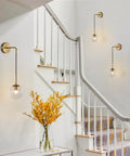 Mid Century Modern Globe Wall Sconce In Brushed Brass Gold With Clear Glass Bubble Ball Bathroom Vanity Bedside Light Fixture Vintage Style Wall Lighting For Living Room illuminating a white staircase