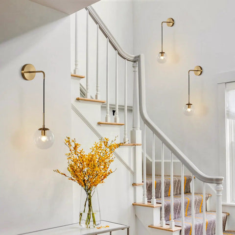 Mid Century Modern Globe Wall Sconce In Brushed Brass Gold With Clear Glass Bubble Ball Bathroom Vanity Bedside Light Fixture Vintage Style Wall Lighting For Living Room illuminating a white staircase