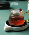 Solid Pick Mug Warmer And 200W Cup Heater That Keeps Your Daily Grind Steaming Hot Up To 100C With Five Precise Temperature Levels Plus Non Slip Base For Desk with tea-filled glass cup on heating base.
