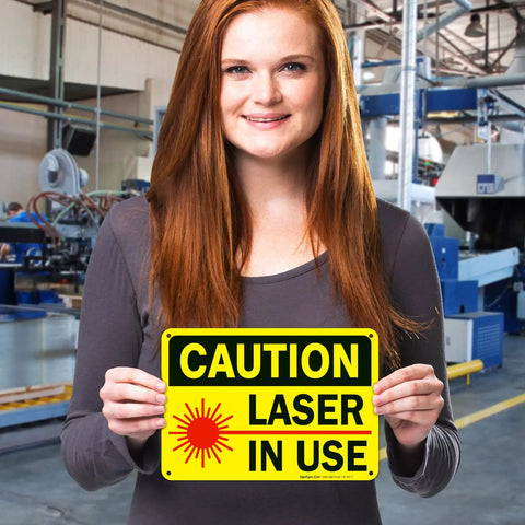 Woman holding "Laser In Use Sign Caution Sign 10x7 Inches Rust Free Aluminum Fade Resistant Indoor Outdoor Safety Sign For Shops And Factories And Industrial Spaces Made In USA" in workshop