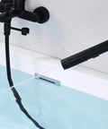 Wall Mount Bathtub Faucet With Handheld Shower And 59 Inch Hose Sleek Black Finish in use, showing water flowing into tub.