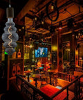 Beehive Style 4W Dimmable LED Edison Bulb with Oversized Spiral Filament, Smoky Grey Glass, in a dimly lit bar setting.