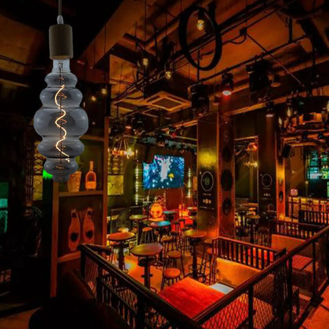 Beehive Style 4W Dimmable LED Edison Bulb with Oversized Spiral Filament, Smoky Grey Glass, in a dimly lit bar setting.