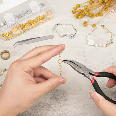 Hands using pliers from 1200 Piece Jump Rings Jewelry Making Kit With Pro Grade Open Close Tools Pliers Tweezers Lobster Clasps And Necklace Repair Set In Silver And Gold Includes 4 5 6 7 8 Mm Sizes For Crafts And Key Chains working on a chain.