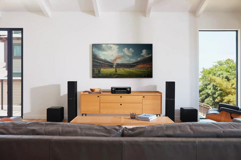 Living room with 7.2 Channel AV Receiver with Built-In HEOS and 8K HDMI Dope Wireless Streaming Dolby Atmos HDR10 Plus Dynamic HDR DTS X WiFi and Bluetooth Plug and Play Setup for Small to Medium Rooms and Smart Home Vibes on a wooden cabinet, surrounded by speakers.