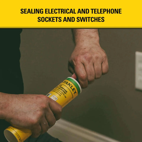 Hands opening a tube of sealant for sealing electrical sockets, with yellow label, in a home setting.
