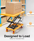 Orange hydraulic lift table cart with four caster wheels carrying a large cardboard box.