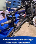 Tool setup for removing needle bearings from VW front beam in a workshop setting.