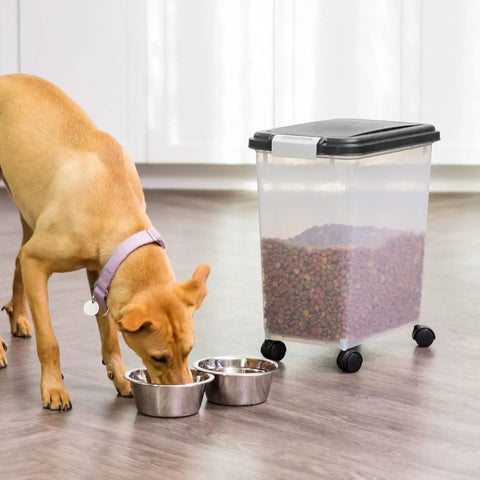 Dog eating next to Air Tight Pet Food Storage Bin With Wheels Makes Kibble Management A No Brainer Holds 22 To 26 Lbs Of Dry Kibble