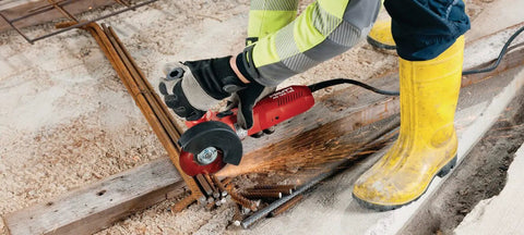Worker using Professional Grade 1300W 230V Angle Grinder Featuring 125MM Disc Size for metal cutting on construction site.
