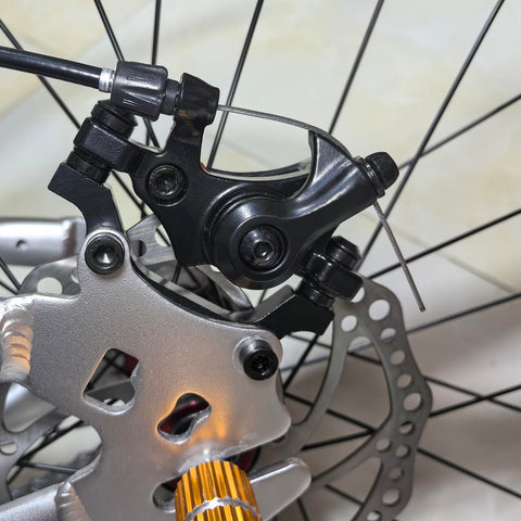 Close-up of bike's front mechanical disc brake caliper with 160mm rotor, part of Front And Rear Bike Disc Brake Kit With 160mm Rotors Calipers Cables Levers And Fixing Screws Stainless Steel Mechanical System For Upgrading Bikes For Daily Ride And Reliable Stopping.