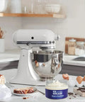 Food Grade Grease For Stand Mixer 4 Oz NSF Certified jar next to a white stand mixer in a kitchen setting