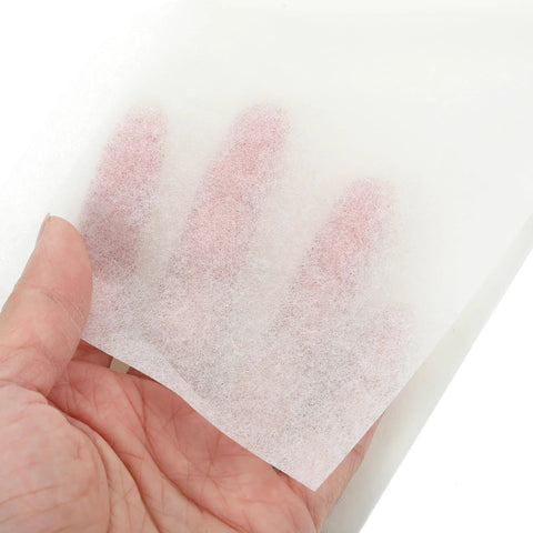 Hand-held sheet of white lens cleaning paper (10×15 cm) for eyeglasses and camera lenses.