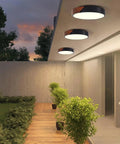 Outdoor view of Slick Modern Black Wood Look Flush Mount Ceiling Light 3 Light Fixture illuminating a patio at dusk.