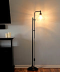 Tall Industrial LED Floor Lamp With Adjustable Head And Rustic Glass Teardrop Shade, Black Finish, in living room corner.