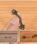 Close-up of an Antique Bronze Cabinet Pull from the 20-Piece Set, Mini Vintage Drawer Handle 47x14mm, showcased on wood surface.