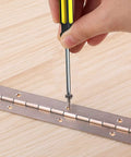 Continuous piano hinge being screwed to a wooden surface; stainless steel, 18-inch length.