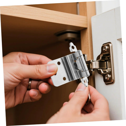Close-up of a silver inset cabinet hinge installed on a wooden door; self-closing, metal mounting plate.