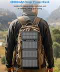 All-In-One Solar Power Bank 49800mAh with 4 Built-In Cables and 3 Foldable Panels attached to a hiker's backpack in nature