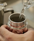 Pouring water into the Hella Durable Stainless Steel Stovetop Espresso Maker for rich coffee brews in a kitchen setting.