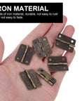 Hand holding 20 Pack Antique Copper Mini Hinges With Screws 1 Inch Rounded Corner Iron Hardware For Wooden Jewelry Boxes Bird Houses
