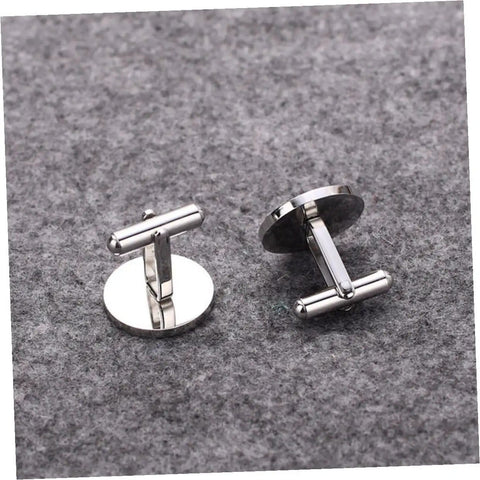 Pair of silver cufflinks on grey fabric background, circular design suitable for formal and business shirts