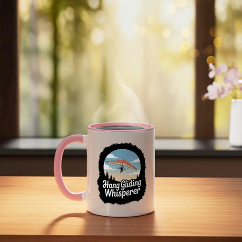 Hang Glider Whisperer Ceramic Mug with Bold Sky Art in Pink and White on wooden table with outdoor window view.