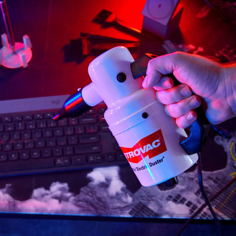 Hand holding Powerful Computer Duster and Cleaner for Electronics and Home Use, high velocity air blower near keyboard.