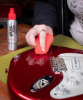 Person using Complete Guitar Care Kit And Clean Polish Set With Fretboard Conditioner on a red electric guitar surface.
