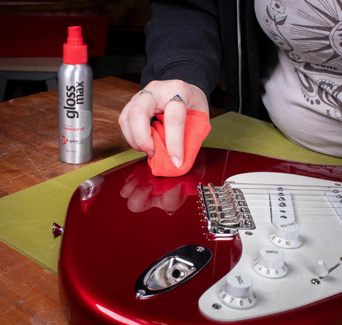Person using Complete Guitar Care Kit And Clean Polish Set With Fretboard Conditioner on a red electric guitar surface.