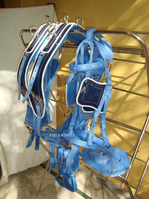 Two Tone Synthetic Patent Leather Driving Harness For Double Horse Cart With Extra Padding Double Layer Nose Band And Hand Carved Saddle And Bridle In Blue And Black displayed on a rack