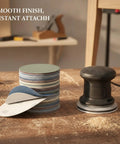 Heavy Duty Aluminum Oxide Sanding Discs With Flexible Backing For Tough Cutting And Smooth Finishes On Wood Metal Or Paint That Resist Tearing And Conform Perfectly To Weird Shapes Without Gunking Up Your Drill Today, shown with a sander on a workbench.
