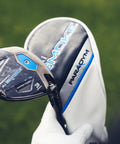Close-up of Paradym AI Smoke Max Fairway 3 Wood Graphite Shaft Stiff Flex with club cover in a hand on grassy background.