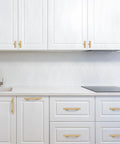 Modern kitchen featuring 6-Pack Solid Brass Cabinet Pulls in Brushed Gold Finish, single hole centers, on white cabinets.