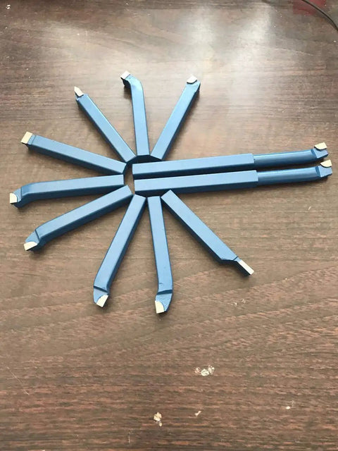 Top Shelf 11 Piece Tungsten Carbide Lathe Turning Tool Set With Heavy Duty Boring Bars and Roughing Grooving Inserts laid out on a wooden surface.