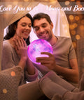 Couple admiring 7.1 Inch Galaxy Moon Lamp 3D Printed Moon With NASA Imagery, 16 Color Changes, in cozy room setting.